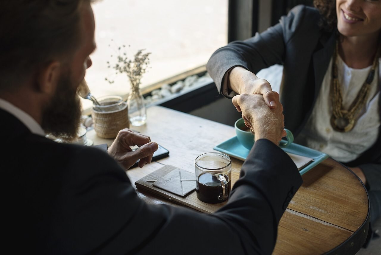 Business partners shaking hands over an agreement at a coffee shop