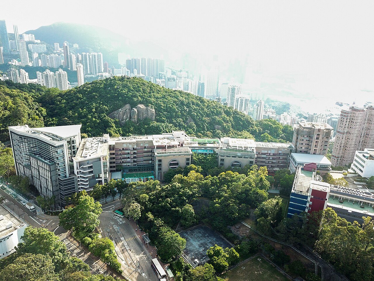 A green international-school campus surrounded by high-rise residential towers in a major Chinese city.